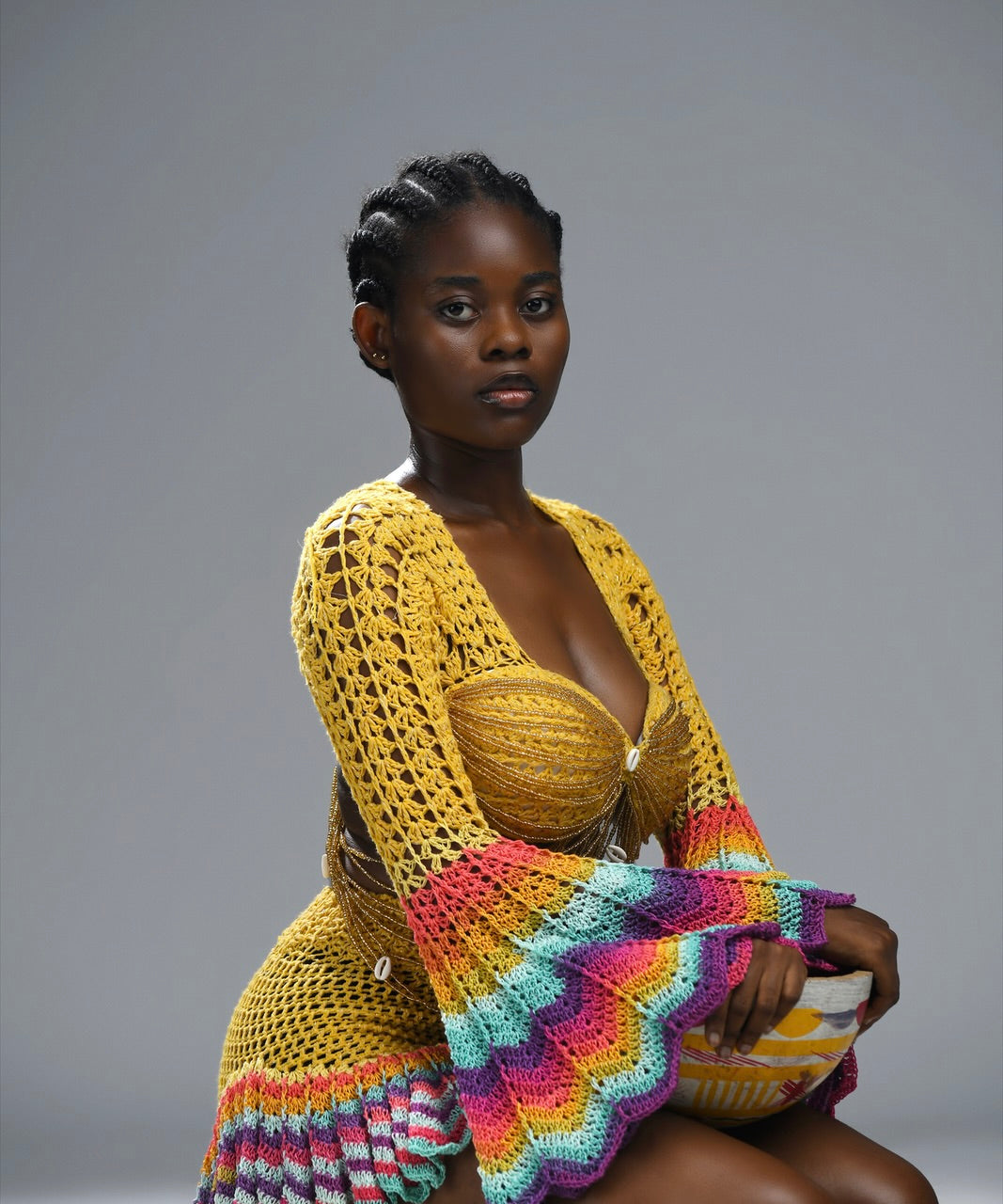Woman wearing a colorful knitted garment on a gray background