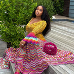 veekee james wearing hookedbylade crochet outfit in yellow and rainbow mix maxi sitting down